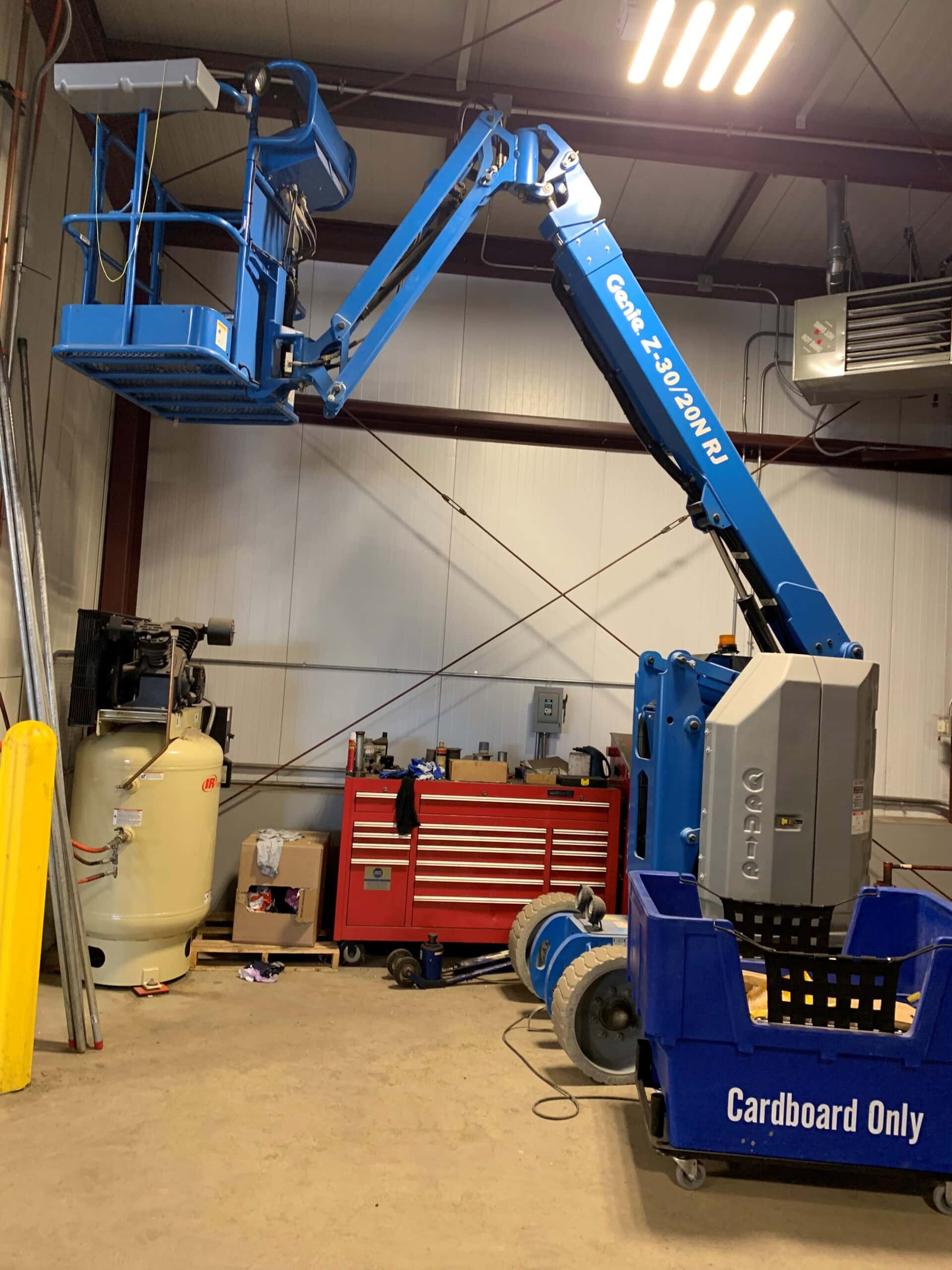 A blue lift truck is parked in a garage.